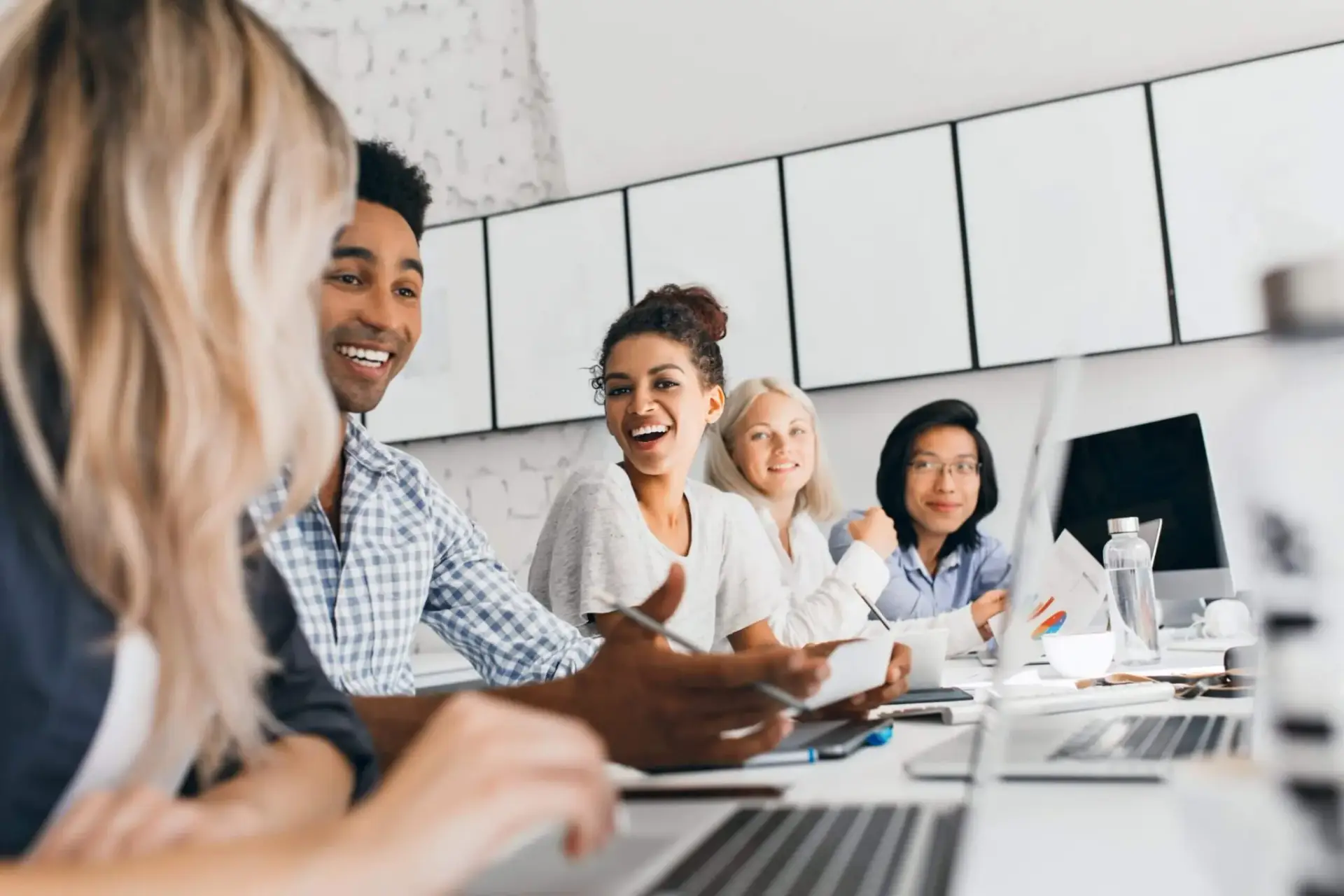 Enthusiastic team of young professionals from Bnternet digital marketing agency engaging in a collaborative meeting around a table with laptops and notes